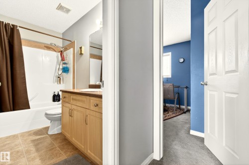 Bathroom with a white tub and shower surround featuring a tiled accent trim - 8922 5Av, Edmonton, AB - Indoor Photo Showing Bathroom