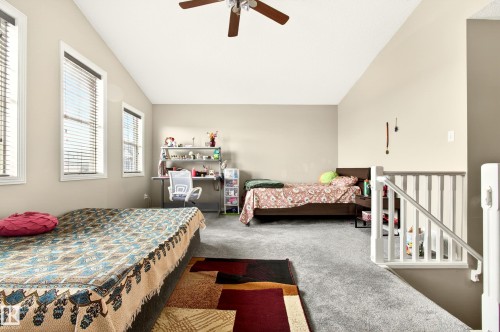 Spacious room featuring vaulted ceilings, plush grey carpeting, and multiple windows with blinds - 8922 5Av, Edmonton, AB - Indoor Photo Showing Bedroom
