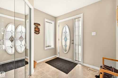 Entryway featuring a decorative oval-inset door, a corresponding sidelight, and neutral wall tones - 8922 5Av, Edmonton, AB - Indoor Photo Showing Other Room
