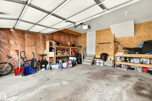 Spacious garage featuring a concrete floor, exposed wood structural elements, and a white overhead garage door - 8922 5Av, Edmonton, AB - Indoor Photo Showing Garage