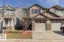 Townhome exterior featuring stone accents, siding, and an attached garage with a concrete driveway - 14 9350 211 Street, Edmonton, AB  - Outdoor With Facade 