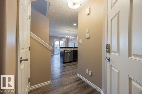 Entryway featuring wood-finish flooring, a white paneled door with a digital lock, and neutral-toned walls - 14 9350 211 Street, Edmonton, AB - Indoor Photo Showing Other Room