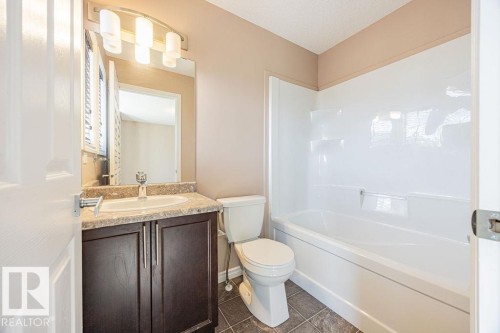 Bathroom featuring a dark wood-finish vanity with a light-colored countertop, an undermount sink, and a chrome faucet - 14 9350 211 Street, Edmonton, AB - Indoor Photo Showing Bathroom