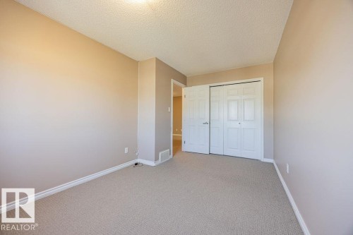 Neutral-toned room featuring light beige carpeting, white baseboards, and a textured ceiling - 14 9350 211 Street, Edmonton, AB - Indoor Photo Showing Other Room