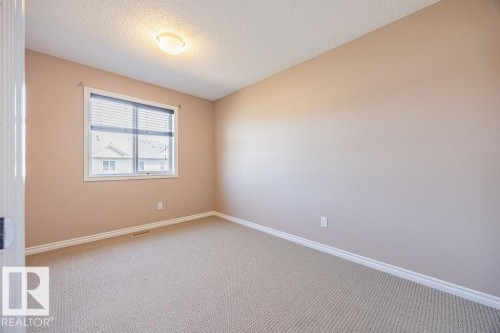 Neutral-toned interior room featuring wall-to-wall carpeting, a single window with horizontal blinds, and a ceiling-mounted light fixture - 14 9350 211 Street, Edmonton, AB - Indoor Photo Showing Other Room