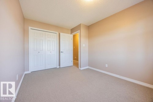 Room with neutral-toned walls, textured ceiling, and light-colored carpet flooring - 14 9350 211 Street, Edmonton, AB - Indoor Photo Showing Other Room