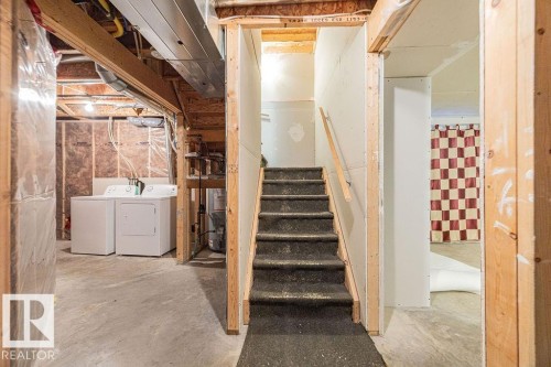 Staircase with carpeted treads and wood handrail, leading to an upper level - 14 9350 211 Street, Edmonton, AB - Indoor Photo Showing Laundry Room