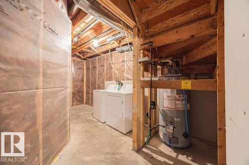 Utility area featuring a water heater, exposed wood framing, and concrete flooring - 14 9350 211 Street, Edmonton, AB - Indoor Photo Showing Laundry Room