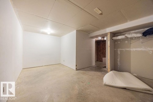 Unfinished lower level space with concrete flooring, white painted walls, and an exposed ceiling - 14 9350 211 Street, Edmonton, AB - Indoor
