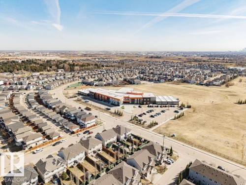 Aerial perspective showcasing a residential community with numerous detached homes, a large commercial building, and undeveloped land - 14 9350 211 Street, Edmonton, AB - Outdoor With View