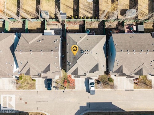 Townhome featuring a shingle roof, paved driveway, and established front landscaping - 14 9350 211 Street, Edmonton, AB - Outdoor