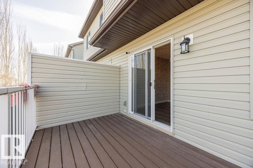 Outdoor deck with composite wood-finish flooring, white railing, and privacy wall - 14 9350 211 Street, Edmonton, AB - Outdoor With Exterior