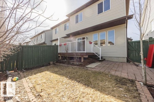 Rear exterior featuring a raised wood-finish deck with white railings, multiple windows, and light-toned siding - 14 9350 211 Street, Edmonton, AB - Outdoor With Exterior