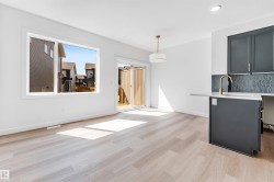 Open-concept living space featuring wood-finish flooring, a large window, and a sliding glass door - 