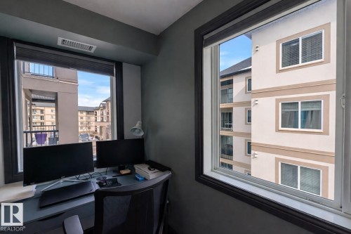 This room features windows with views of other residential buildings and a balcony - 324 13111 140 Avenue, Edmonton, AB - Indoor Photo Showing Office