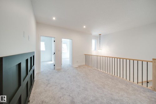 Upper-level landing featuring light gray carpeting, contemporary wooden railing with black balusters, and recessed ceiling lighting - 16 Blackbird Bend, Fort Saskatchewan, AB - Indoor Photo Showing Other Room