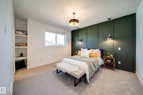 Bedroom featuring a paneled accent wall, recessed shelving, a window, and a ceiling-mounted light fixture - 16 Blackbird Bend, Fort Saskatchewan, AB - Indoor Photo Showing Bedroom