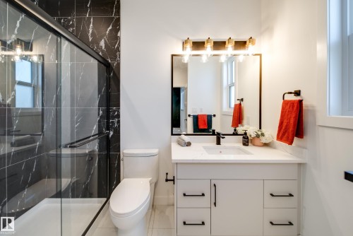 Shower with black marble-style tile surround and glass enclosure - 16 Blackbird Bend, Fort Saskatchewan, AB - Indoor Photo Showing Bathroom