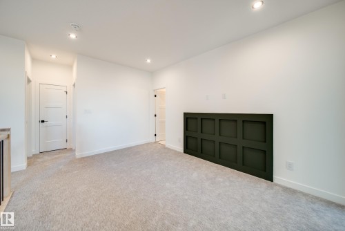Carpeted room featuring a dark green wainscoting accent wall, recessed lighting, white trim, and a three-panel interior door with black hardware - 16 Blackbird Bend, Fort Saskatchewan, AB - Indoor Photo Showing Other Room
