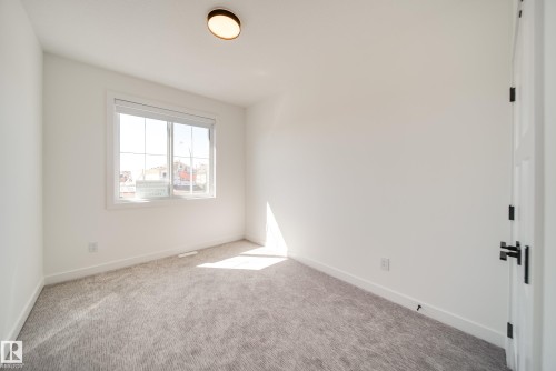 Bright room featuring a large window, plush gray carpeting, crisp white walls, and a contemporary flush-mount ceiling light - 16 Blackbird Bend, Fort Saskatchewan, AB - Indoor Photo Showing Other Room