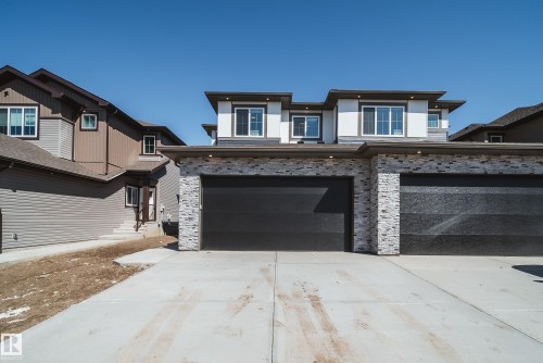 Modern architectural facade featuring stacked stone accents and dark garage doors - 16 Blackbird Bend, Fort Saskatchewan, AB - Outdoor With Facade
