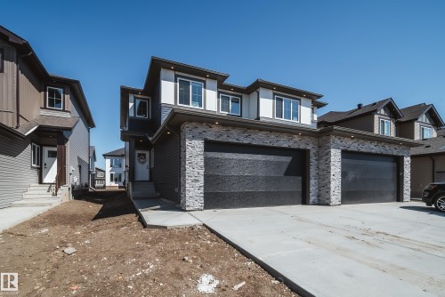 Modern duplex exterior featuring a stone facade and dark horizontal siding - 16 Blackbird Bend, Fort Saskatchewan, AB - Outdoor With Facade