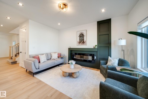 Contemporary living space featuring a built-in linear electric fireplace with a dark green panel accent wall - 16 Blackbird Bend, Fort Saskatchewan, AB - Indoor Photo Showing Living Room With Fireplace