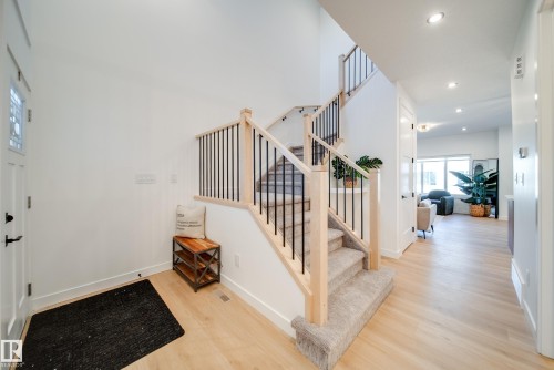 Inviting entry foyer featuring light wood-finish flooring, a contemporary staircase with wood newel posts and black iron balusters, and recessed ceiling lighting - 16 Blackbird Bend, Fort Saskatchewan, AB - Indoor Photo Showing Other Room