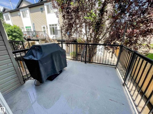 Private balcony featuring a light-colored surface, black metal railings, and mature tree coverage - 5806 118 Avenue Nw, Edmonton, AB - Outdoor With Exterior