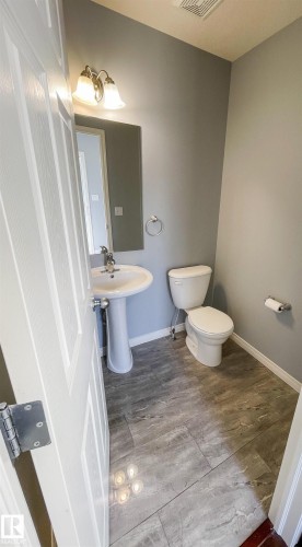 Pedestal sink with chrome faucet, mirror, and brushed nickel light fixture - 5806 118 Avenue Nw, Edmonton, AB - Indoor Photo Showing Bathroom