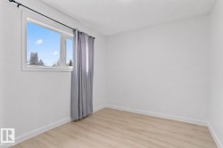 Bright interior space featuring a window with white trim, light wood-finish flooring, and crisp white walls - 