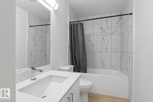 Bathroom featuring a white vanity with integrated sink, chrome faucet, and spacious mirror - 1566 Lakewood Road Nw, Edmonton, AB - Indoor Photo Showing Bathroom