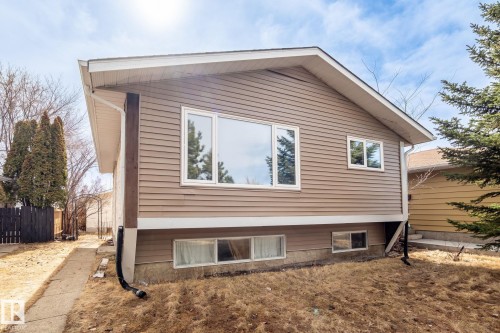 Split-level exterior featuring horizontal siding in a neutral tone, white-framed windows, and a prominent roofline with white soffit and fascia - 1566 Lakewood Road Nw, Edmonton, AB - Outdoor With Exterior
