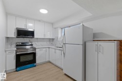 Contemporary kitchen featuring white cabinetry, light countertops, and a white backsplash - 
