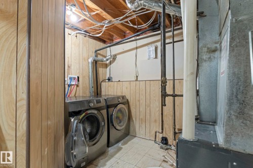 Laundry area featuring wood paneling, exposed ceiling joists, and visible utility lines - 1566 Lakewood Road Nw, Edmonton, AB - Indoor Photo Showing Laundry Room