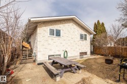 Rear exterior of the property featuring textured stucco siding and a gable roofline - 