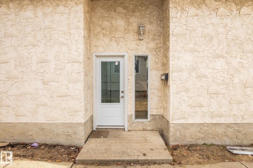 Recessed entryway featuring textured stucco with a shell pattern, a glass-panel entry door, and a vertical glass sidelight - 1566 Lakewood Road Nw, Edmonton, AB - Outdoor