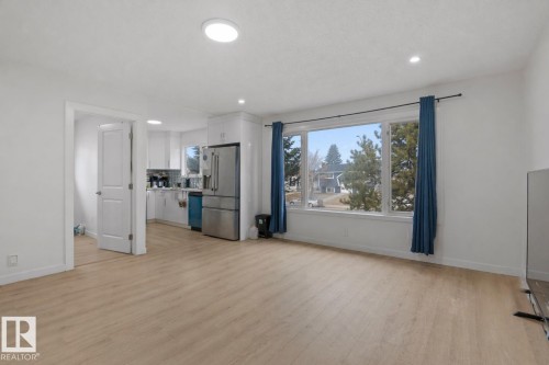 Open-concept living space with light wood-finish flooring, recessed lighting, and a large multi-pane window - 1566 Lakewood Road Nw, Edmonton, AB - Indoor