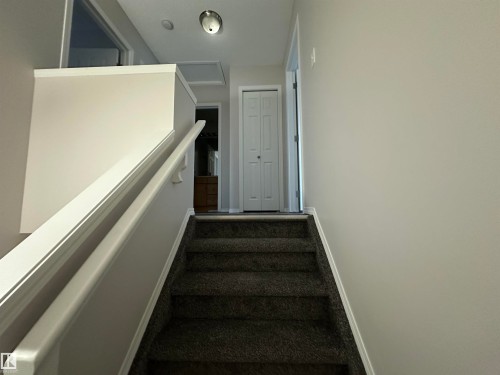Stairway featuring dark carpeting, white handrails, and neutral wall tones - 97 2021 Grantham Crest, Edmonton, AB - Indoor Photo Showing Other Room