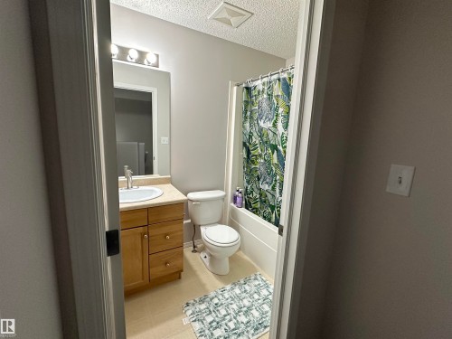 Bathroom featuring a single vanity with wood cabinetry, a light-toned countertop, and an undermount sink - 97 2021 Grantham Crest, Edmonton, AB - Indoor Photo Showing Bathroom