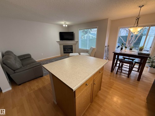 Central kitchen island with light-toned countertop and wood-finish cabinetry - 97 2021 Grantham Crest, Edmonton, AB - Indoor Photo Showing Living Room With Fireplace