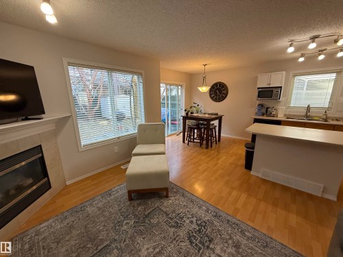 Living area with wood-finish flooring and a corner fireplace featuring a tile surround - 97 2021 Grantham Crest, Edmonton, AB - Indoor Photo Showing Living Room With Fireplace