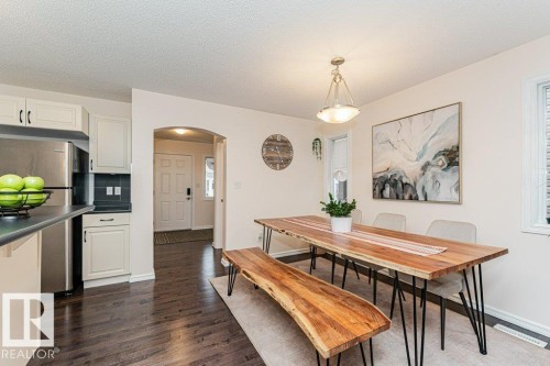 This bright dining area features dark hardwood flooring, a window with blinds, and an arched entryway - 2828 21 Avenue, Edmonton, AB - Indoor Photo Showing Other Room