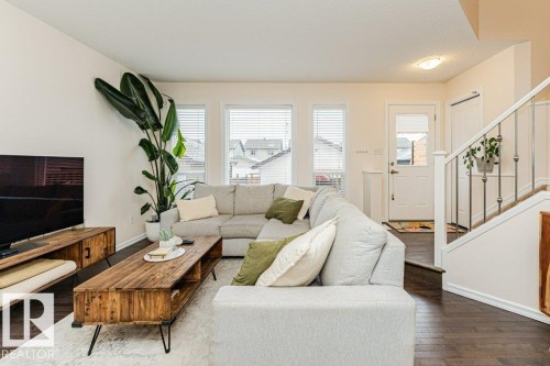 Living area featuring dark hardwood flooring, white walls, and a staircase with white balusters and a dark handrail - 2828 21 Avenue, Edmonton, AB - Indoor Photo Showing Living Room