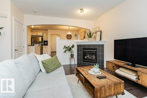 Living area with dark hardwood floors, a tiled fireplace with a white mantel, and an arched doorway leading to another area - 2828 21 Avenue, Edmonton, AB - Indoor Photo Showing Living Room With Fireplace