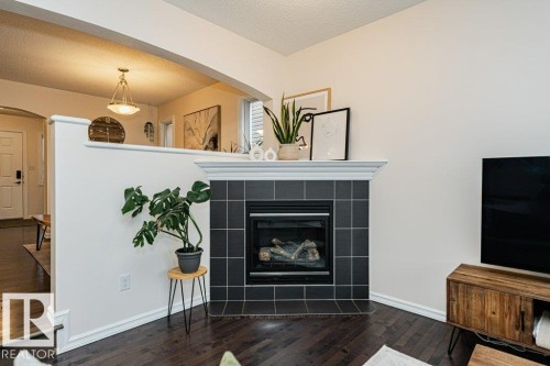 Living area featuring dark hardwood floors, a fireplace with dark tile surround, and an arched entryway - 2828 21 Avenue, Edmonton, AB - Indoor With Fireplace
