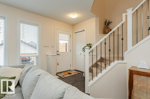 Inviting entry space featuring dark hardwood flooring, a white paneled door with window, and a staircase with white newel posts and metal balusters - 2828 21 Avenue, Edmonton, AB - Indoor Photo Showing Other Room