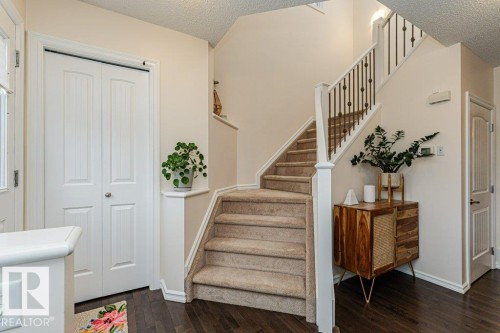 Welcoming entryway featuring dark hardwood flooring, a carpeted staircase with white balusters and dark spindles, and a white bifold door - 2828 21 Avenue, Edmonton, AB - Indoor Photo Showing Other Room