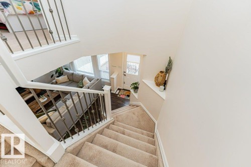 This property features a staircase with carpeted treads and white risers, complemented by a white handrail and decorative metal balusters - 2828 21 Avenue, Edmonton, AB - Indoor