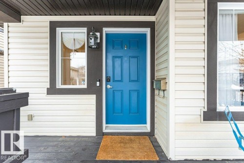 Welcoming front entrance with a vibrant blue door, white siding, and dark trim details - 2828 21 Avenue, Edmonton, AB - Outdoor With Exterior